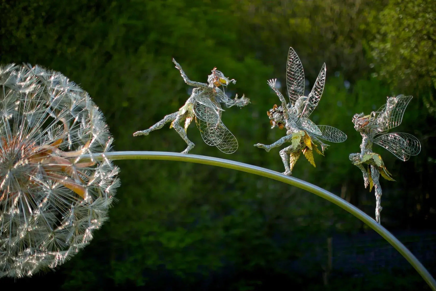 Handcrafted metal fairies dancing across a dandelion garden sculpture